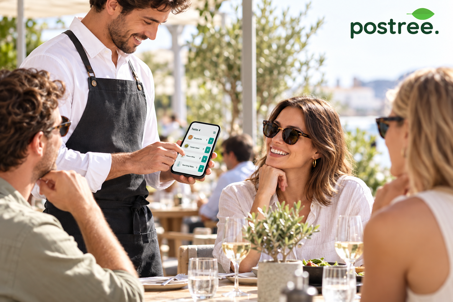 Server using a compact OrderPad beside guests on a restaurant terrace.